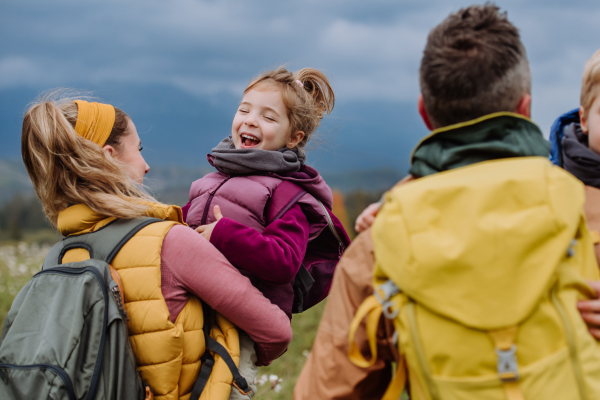 Happy parents with their little kids in arms at autumn walk, in the middle of colourfull nature. Concept of a healthy lifestyle.