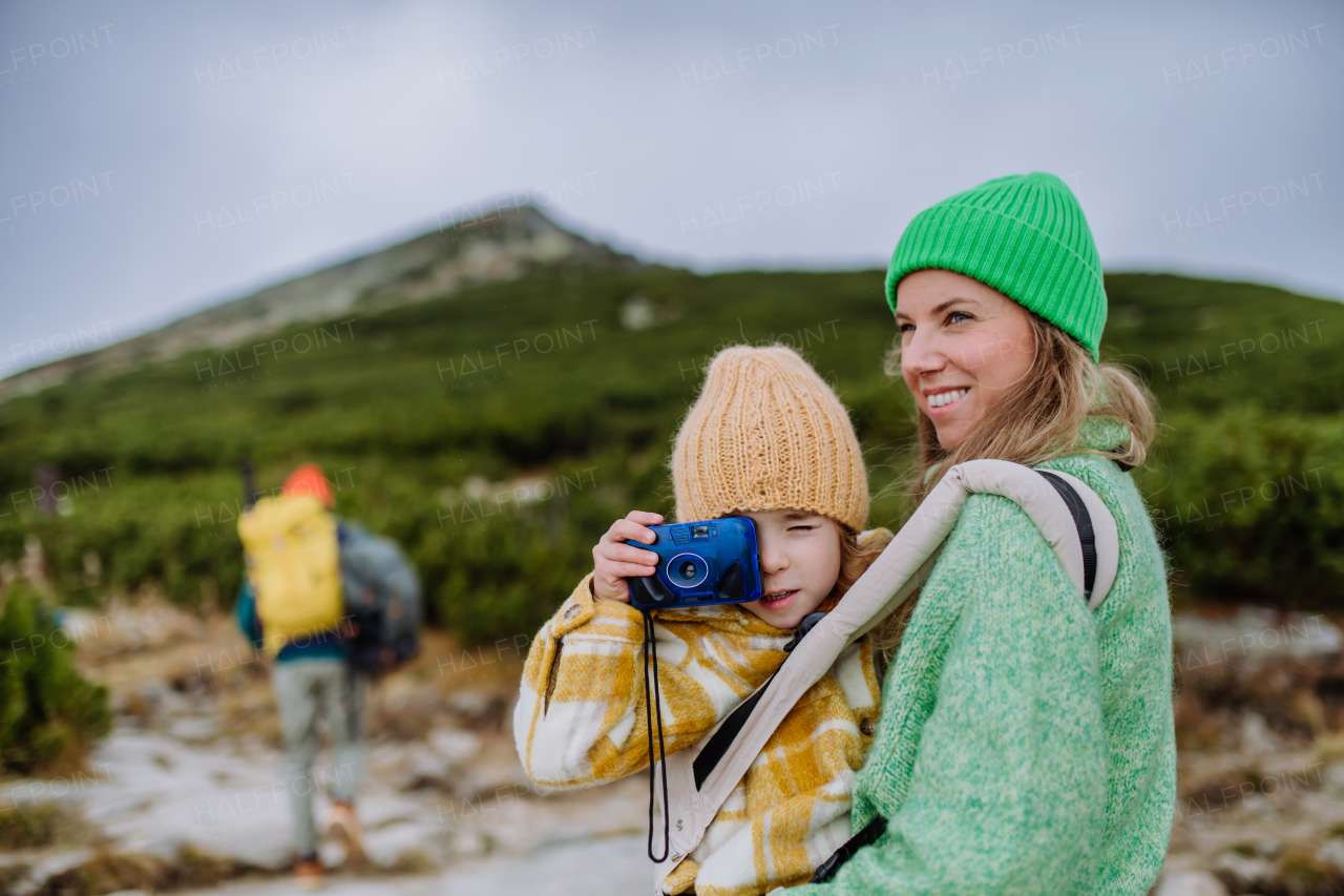 Little girl taking pictures during a hike. Happy family hiking together in an autumn mountains.