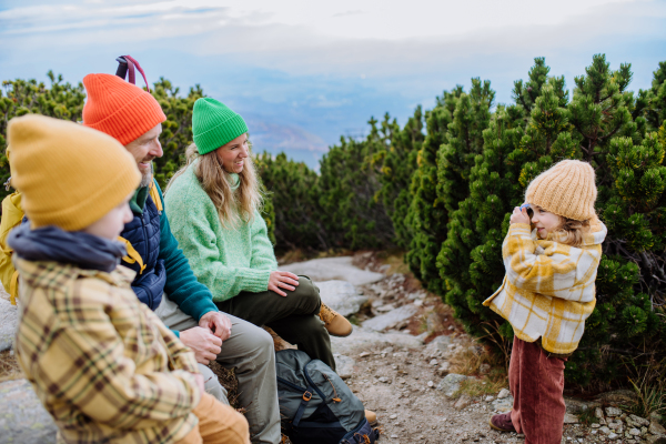 Little girl taking photos of her family, having break during hiking in the mountains.