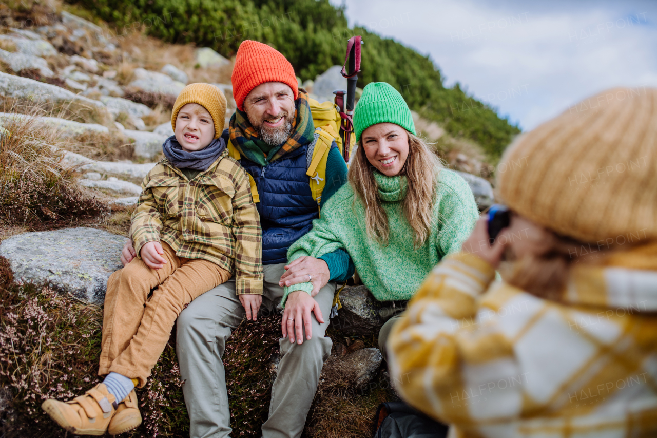 Little girl taking pictures of her family during a hike. Happy family hiking together in an autumn mountains.