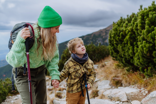 Active mother and little son with trekkiing poles hiking together in an autumn mountains. Hiking with young kids.