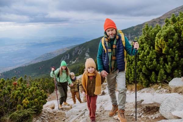 Portrait of happy family with trekkiing poles hiking together in an autumn mountains. Hiking with young kids.