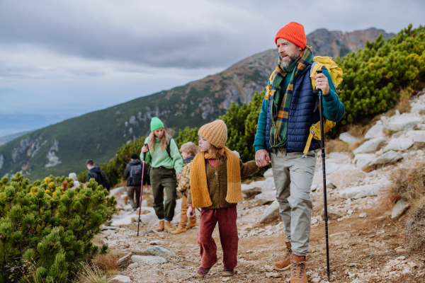 Portrait of happy family with trekkiing poles hiking together in an autumn mountains. Hiking with young kids.