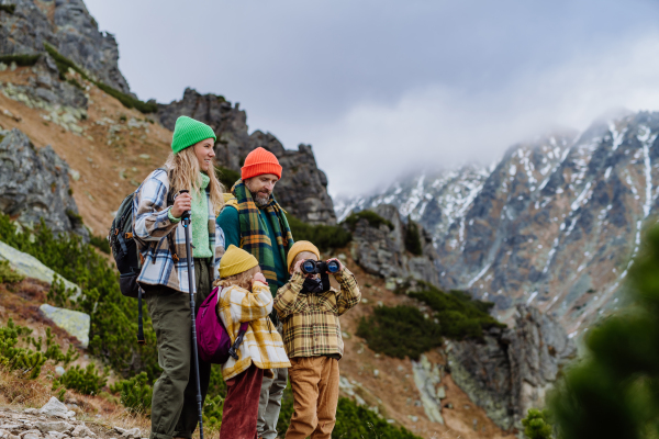 Portrait of happy family hiking together in an autumn mountains. Hiking with young kids. Little boy looking through a binoculars.