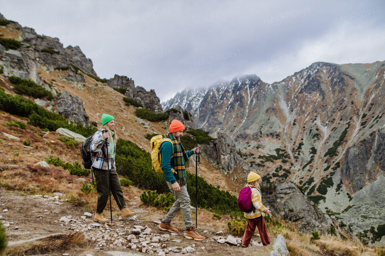 Portrait of happy family with trekkiing poles hiking together in an autumn mountains. Hiking with young kids. Family hikers walking down the hill.