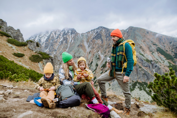 Happy family resting, having snack during hiking together in an autumn mountains.