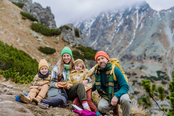 Happy family resting, having snack during hiking together in an autumn mountains.