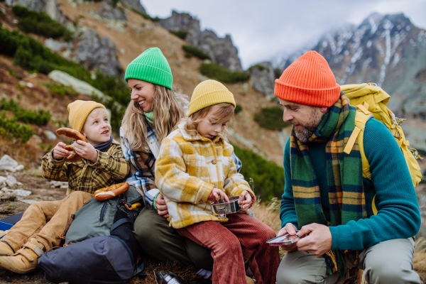 Happy family resting, having snack during hiking together in an autumn mountains.