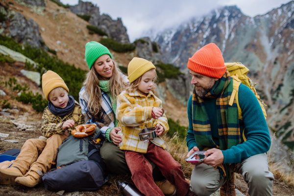 Happy family resting, having snack during hiking together in an autumn mountains.