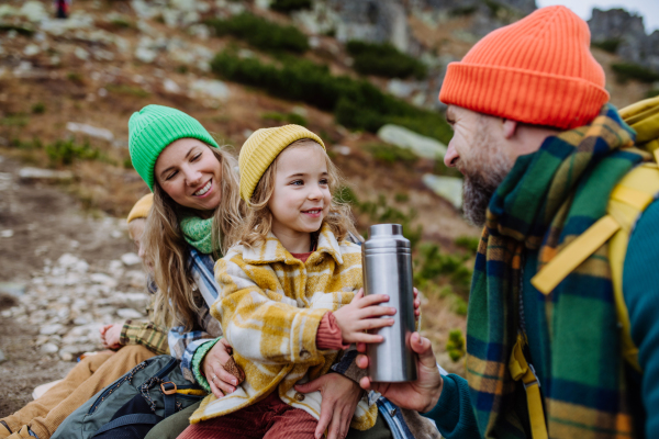 Happy family resting, having snack during hiking together in an autumn mountains.