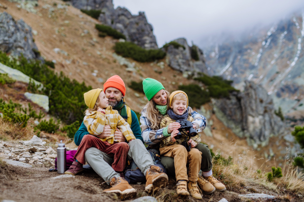 Happy family sitting and resting, during hiking together in an autumn mountains.