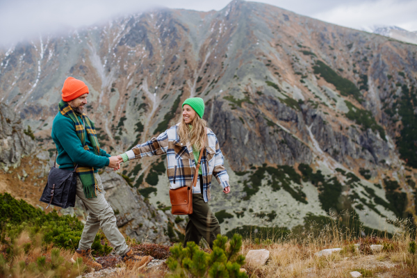 Yung happy couple at a mountain hike, holding hands and looking at each other lovingly. Married couple spending their honeymoons hiking, backpacking, visiting national parks.