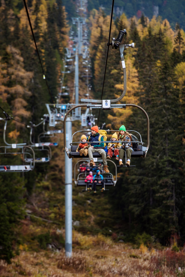 Family sitting inside of cable car and enjoying the view. Mountains with open cable cars lift during the tourist season,