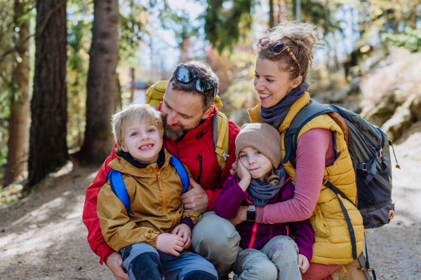 Portrait of happy family hiking together in an autumn mountains. Hiking with young children, on kids friendly trail.