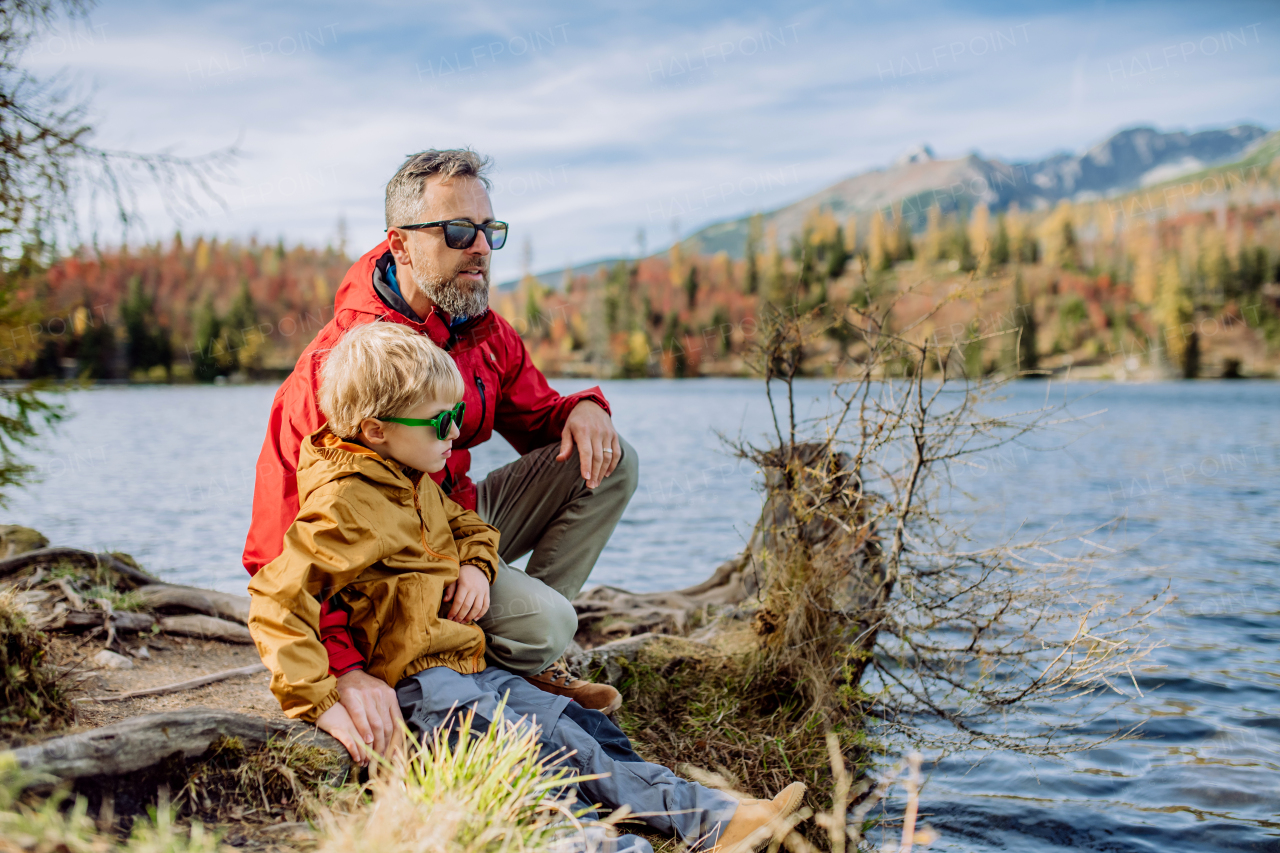 Happy father with his little son, resting near lake in the mountains.