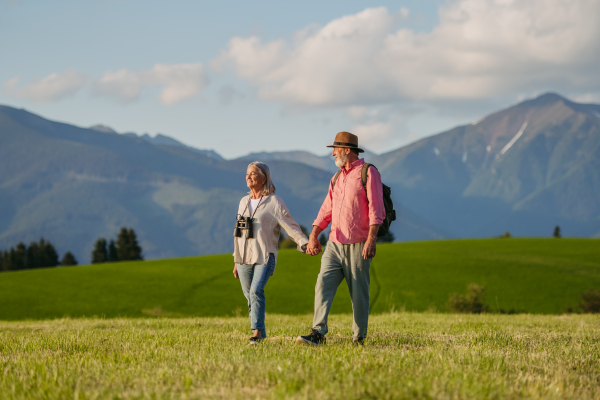 Senior couple walking through the autumn nature. Elderly spouses enjoying the beautiful view of the High Tatras. Minimalist landscape photography with copy space.