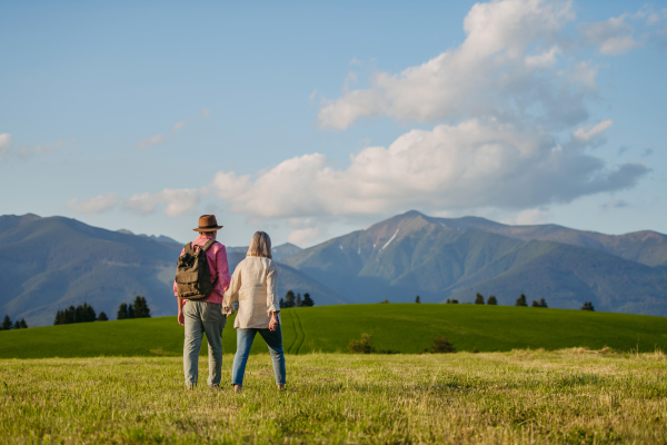 Senior couple walking through the autumn nature. Elderly spouses enjoying the beautiful view of the High Tatras. Minimalist landscape photography with copy space.