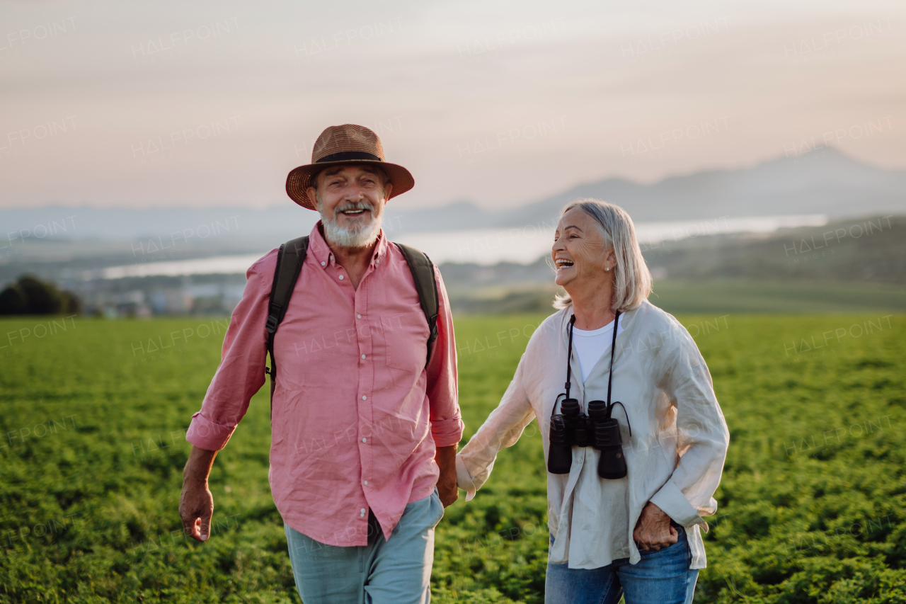 Portrait of senior couple walking through the autumn nature. Elderly spouses going mushroom picking.