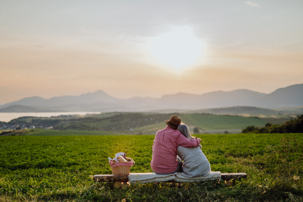 Embracing senior couple watching sunset at the autumn nature. Elderly spouses looking at serene landscape, enjoying beautiful view at High Tatras.