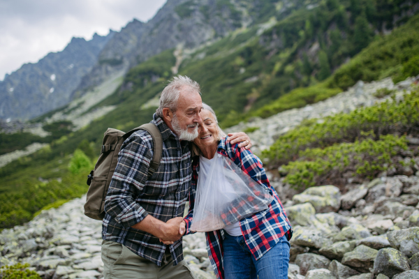 Senior man helping injured woman. A senior woman injured her arm during hike in the mountains. Tourist went off-trail and fell.