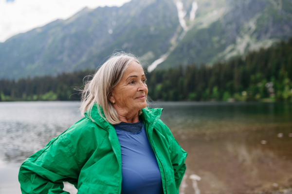 Portrait of beautiful elderly woman in autumn nature. Senior tourist feeling satisfied after hike in mountains.