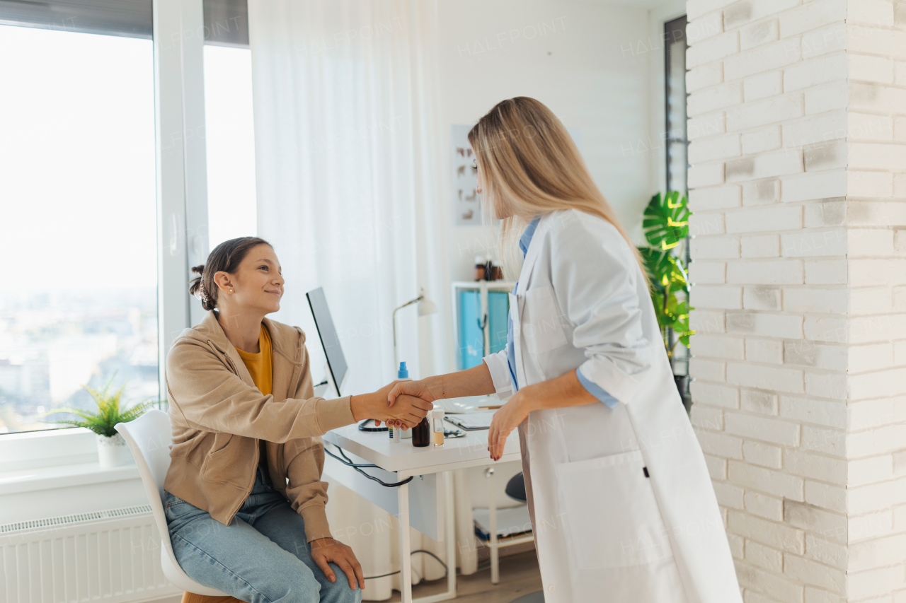 Teenage patient arriving at appointment with the doctor, shaking hands with female pediatrician, physician. Teen girl have consultation, first visit with gynecologist. Concept of preventive health care for adolescents.