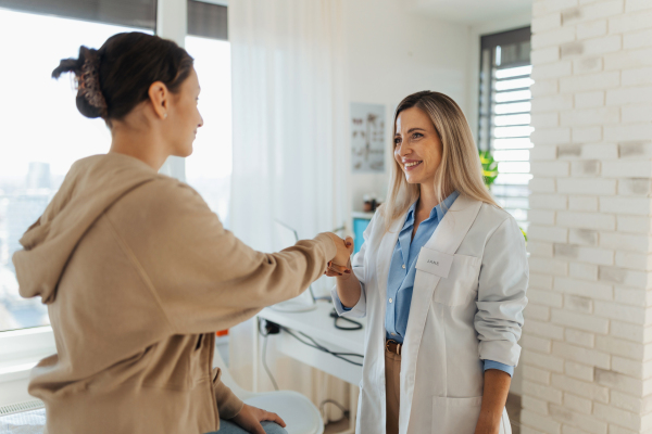 Teenage patient arriving at appointment with the doctor, shaking hands with female pediatrician, physician. Teen girl have consultation, first visit with gynecologist. Concept of preventive health care for adolescents.