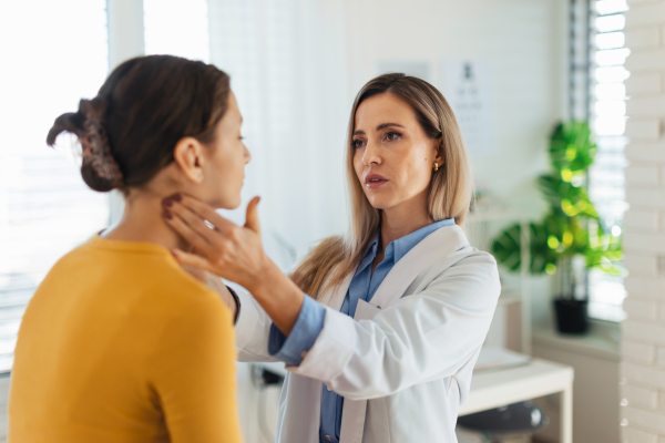 Doctor examining lymp nodes on neck of the teenage girl. Concept of preventive health care for adolescents.