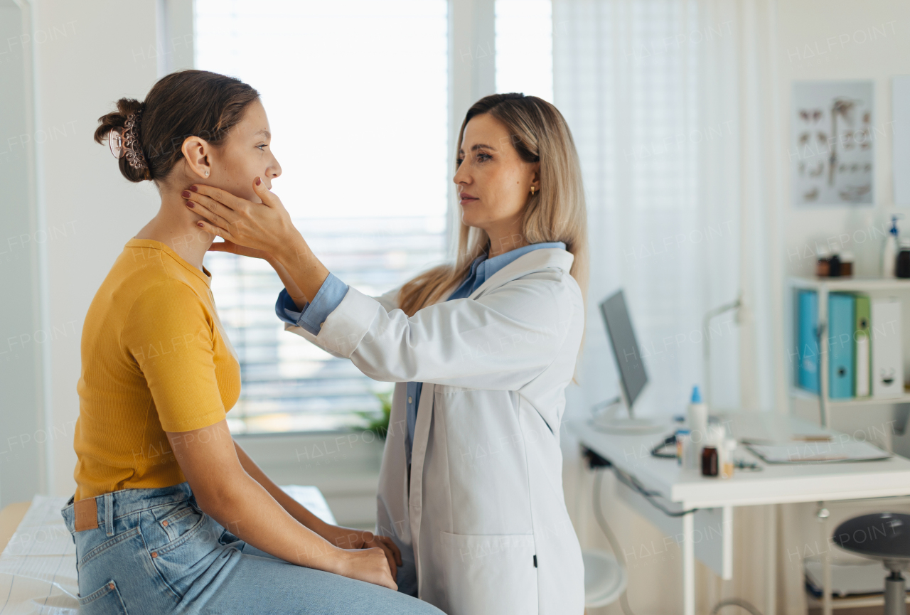 Doctor examining lymp nodes on neck of the teenage girl. Concept of preventive health care for adolescents.