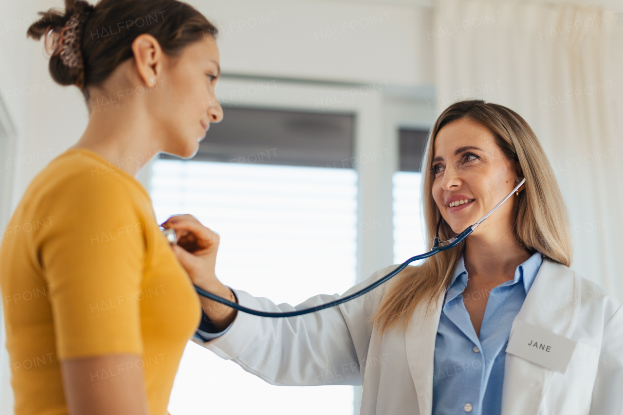 Doctor listening to girls's breathing, heartbeats using a stethoscope. Teenage girl visiting paediatrician for annual preventive physical examination. Concept of preventive health care for adolescents.