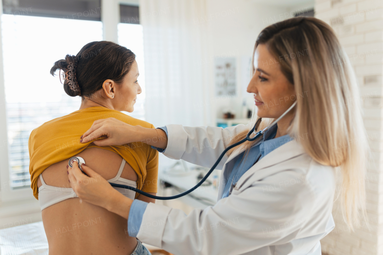 Doctor listening to girls's breathing, heartbeats using a stethoscope. Teenage girl visiting paediatrician for annual preventive physical examination. Concept of preventive health care for adolescents.