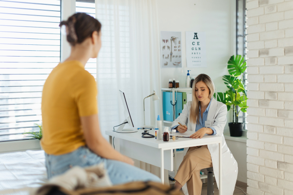 Teenage girl discussing test results with paediatrician. Doctor prescribing medication to ill teenage girl. Concept of preventive health care for adolescents.