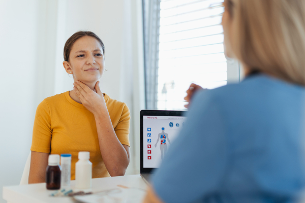 A teenage girl describing her symptoms and pain to the doctor in the clinic. The girl has a sore throat, cough, and pain when swallowing.