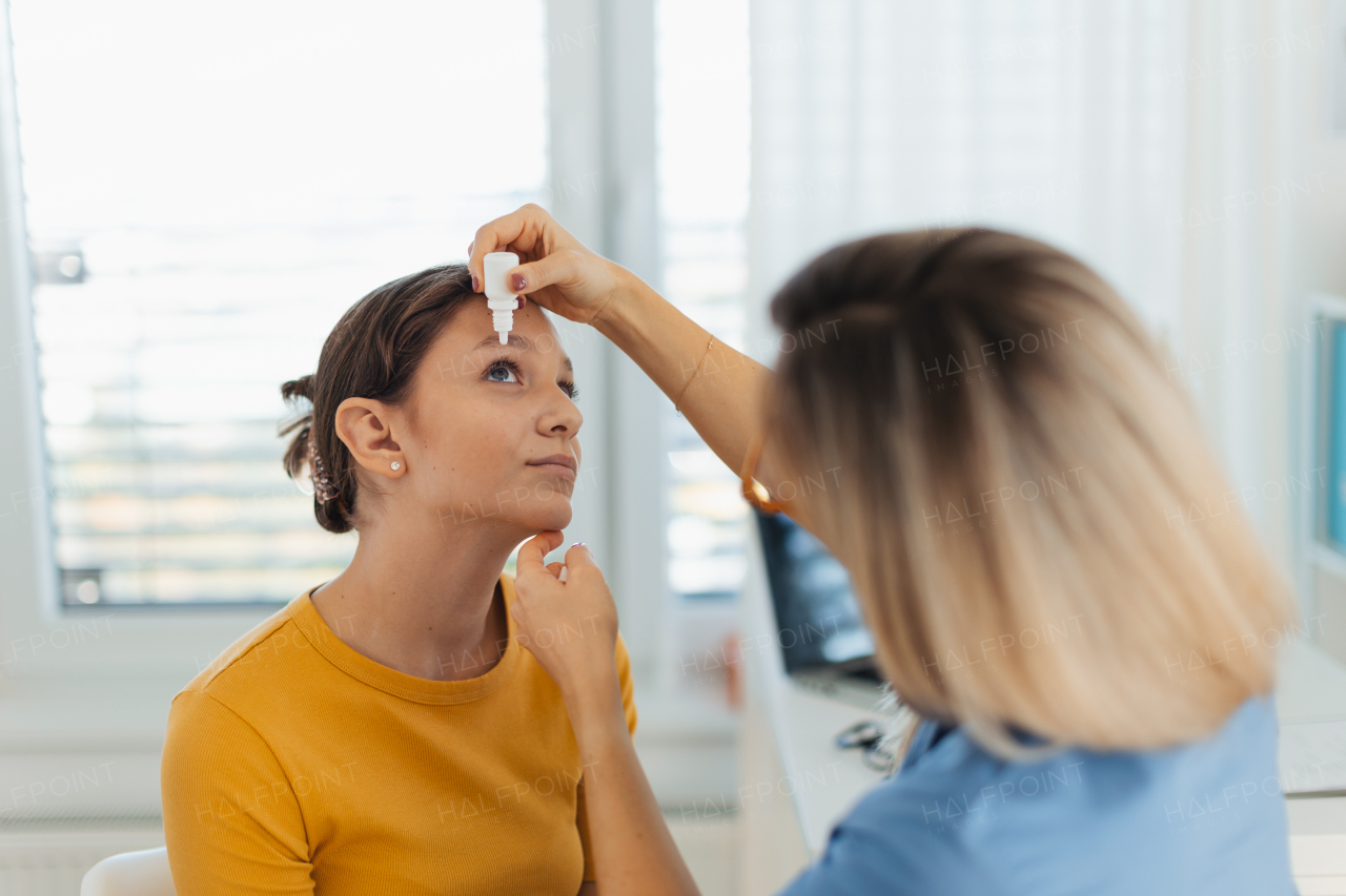 Pediatrician putting eye drops into girls eyes. Ophthalmologist treating an eye infection, allergy, or inflammation using prescribed eye drops.