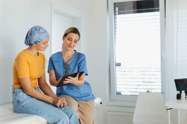 Teenage oncology patient talking with the doctor. Oncologist treating teen girl with cancer and provide emotional support, helping her with anxiety and depression.