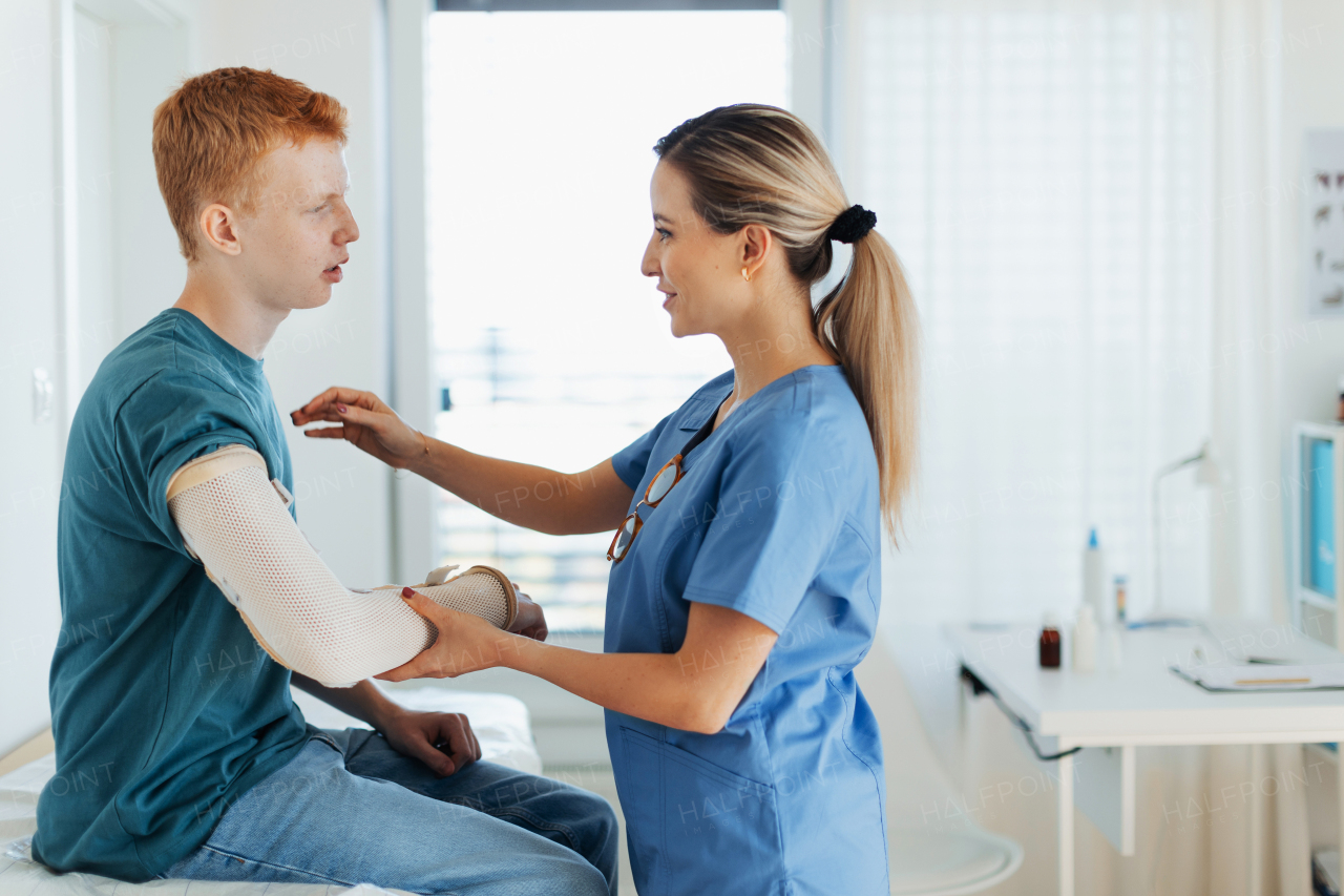 Doctor checking orthopedic cast, brace on a teenage patient's broken arm. Teenage boy is healing a fracture after an accident.