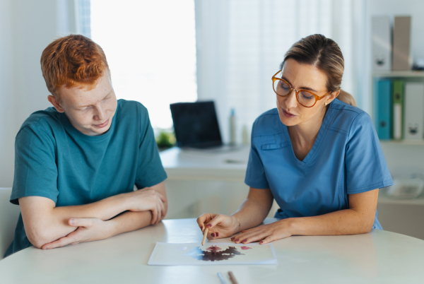 Teenager taking Rorschach test during psychological therapy with adolescent psychologist. Psychological session for teenage boy. Concept of teen mental health and unique adolescent problems.