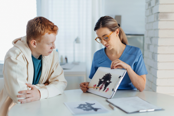 Teenager taking Rorschach test during psychological therapy with adolescent psychologist. Psychological session for teenage boy. Concept of teen mental health and unique adolescent problems.