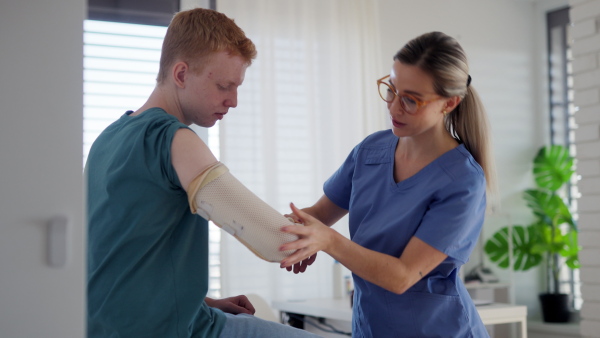 Doctor checking orthopedic cast, brace on a teenage patient's broken arm. Teenage boy is healing a fracture after an accident.