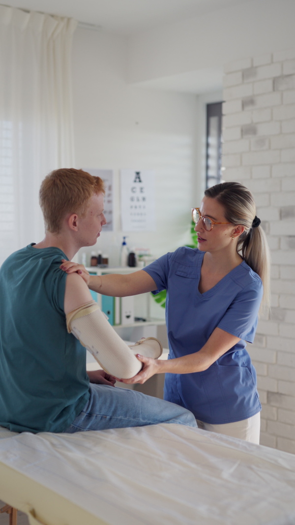 Doctor checking orthopedic cast, brace on a teenage patient's broken arm. Teenage boy is healing a fracture after an accident.