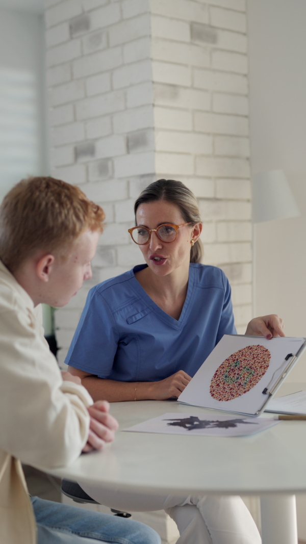 Ophthalmologist examining teenage boys's vision, doing Ishihara colour test. Eye doctor checking health of eyes and vision of teenage patient. Annual eye check up, ophthalmic exam for adolescents.