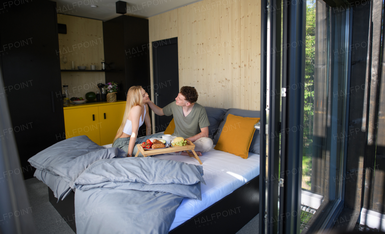 A young beautiful couple in love is sitting in bed and having healthy breakfast together.