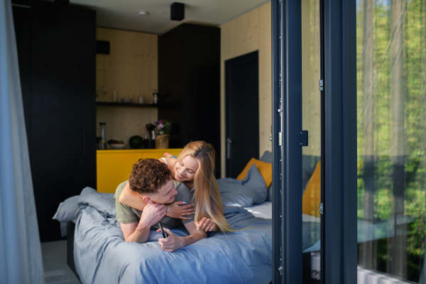 A Young happy couple in love lying in bed in morning in their new home in tiny house,sustainable living concept.