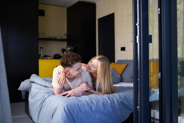 A Young happy couple in love lying in bed in morning in their new home in tiny house,sustainable living concept.