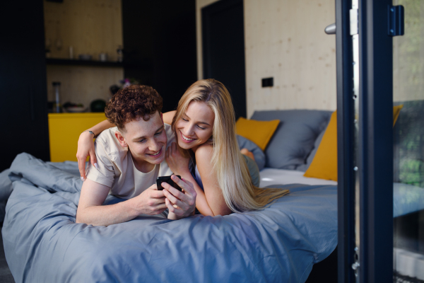 A Young happy couple in love lying in bed in morning in their new home in tiny house,sustainable living concept.