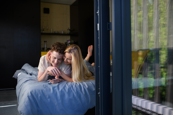 A Young happy couple in love lying in bed in morning in their new home in tiny house,sustainable living concept.