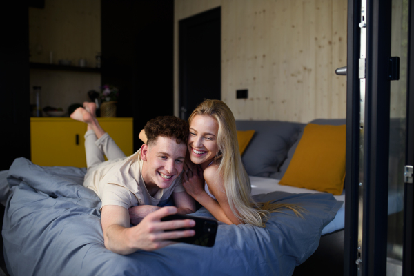 A Young happy couple in love lying in bed in morning in their new home in tiny house,sustainable living concept.