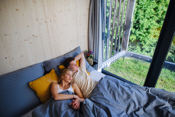 A Young happy couple in love lying in bed in morning in their new home in tiny house,sustainable living concept.