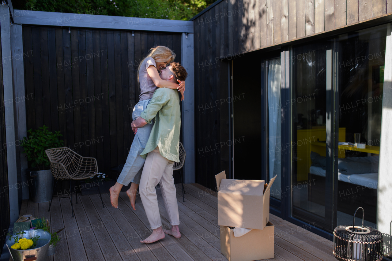 A cheerful young couple moving in their new tiny house in woods. Conception of moving and sustainable living.