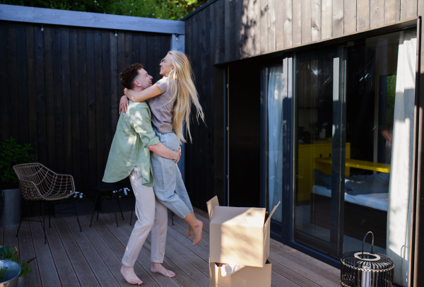 A cheerful young couple moving in their new tiny house in woods. Conception of moving and sustainable living.